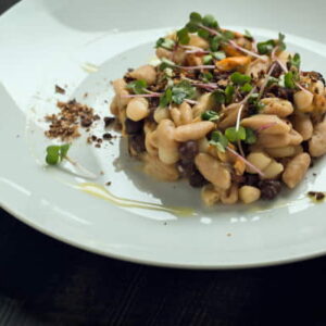 scelto con gusto - Cuocete in due pentole separate i fagioli e i ceci neri (messi in acqua dal giorno prima) in una pentola con acqua, cipolla, alloro e sedano. Fate dorare leggermente in padella uno spicchio d’aglio e un gambo di prezzemolo e fate aprire le cozze. Appena aperte, spegnete il fuoco e ricavatene solo il frutto. Filtrate il brodo e mettere da parte. Prendete 20 gr di ceci neri lessi, sciacquateli sotto acqua corrente, asciugateli e stendeteli in teglia su carta forno, infornate a 100 gradi per 1 ora circa e successivamente passateli al minipimer. Mettete in una padella il brodetto di cozze precedentemente filtrato, portatelo a bollore e versatevi i cavatelli. Aggiungetevi quindii fagioli e ceci neri lessi. A fine cottura aggiungete le cozze a frutto e mantecate con un filo di olio evo. Impiattate terminando con una spolverata di ceci neri esiccati.